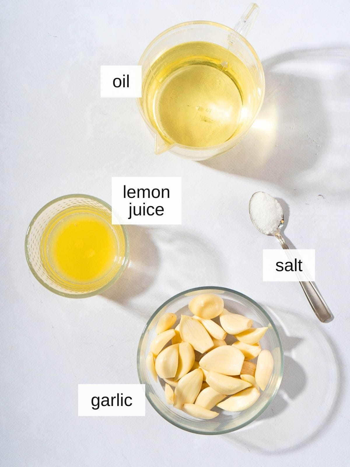ingredients for toum garlic mayo recipe, including oil, lemon juice, salt, and garlic.