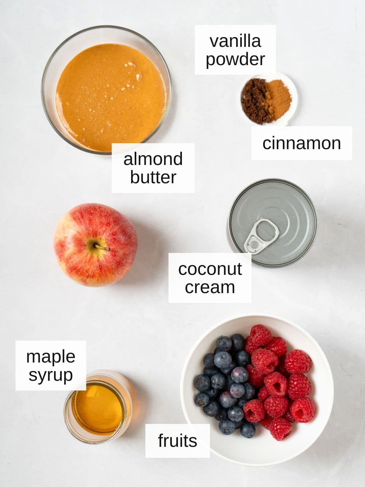 ingredients for vegan fruit dip, including almond butter, vanilla powder, cinnamon, coconut cream, maple syrup, and dippable fruits.