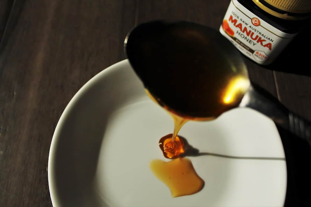 Manuka honey being poured on a plate from a spoon. 