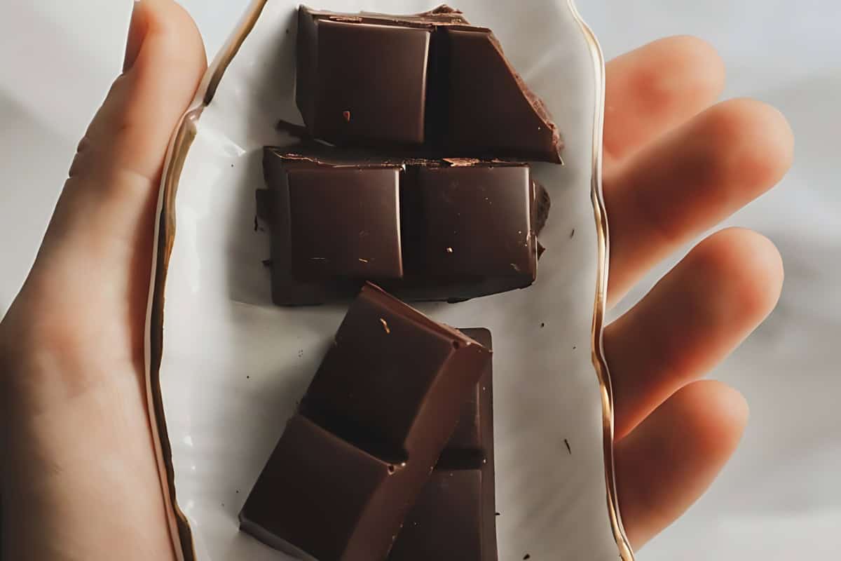 Chopped chocolate bars on a plate being held by a person. 