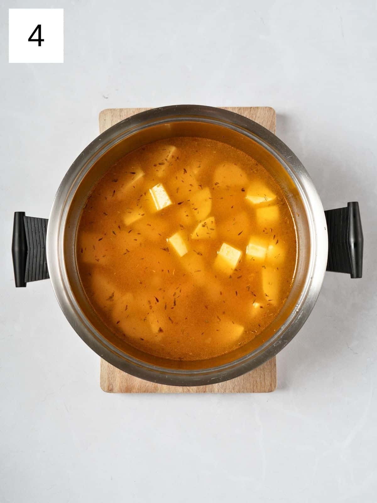 a mixture of vegetable broth and seasoned potatoes in a pot.