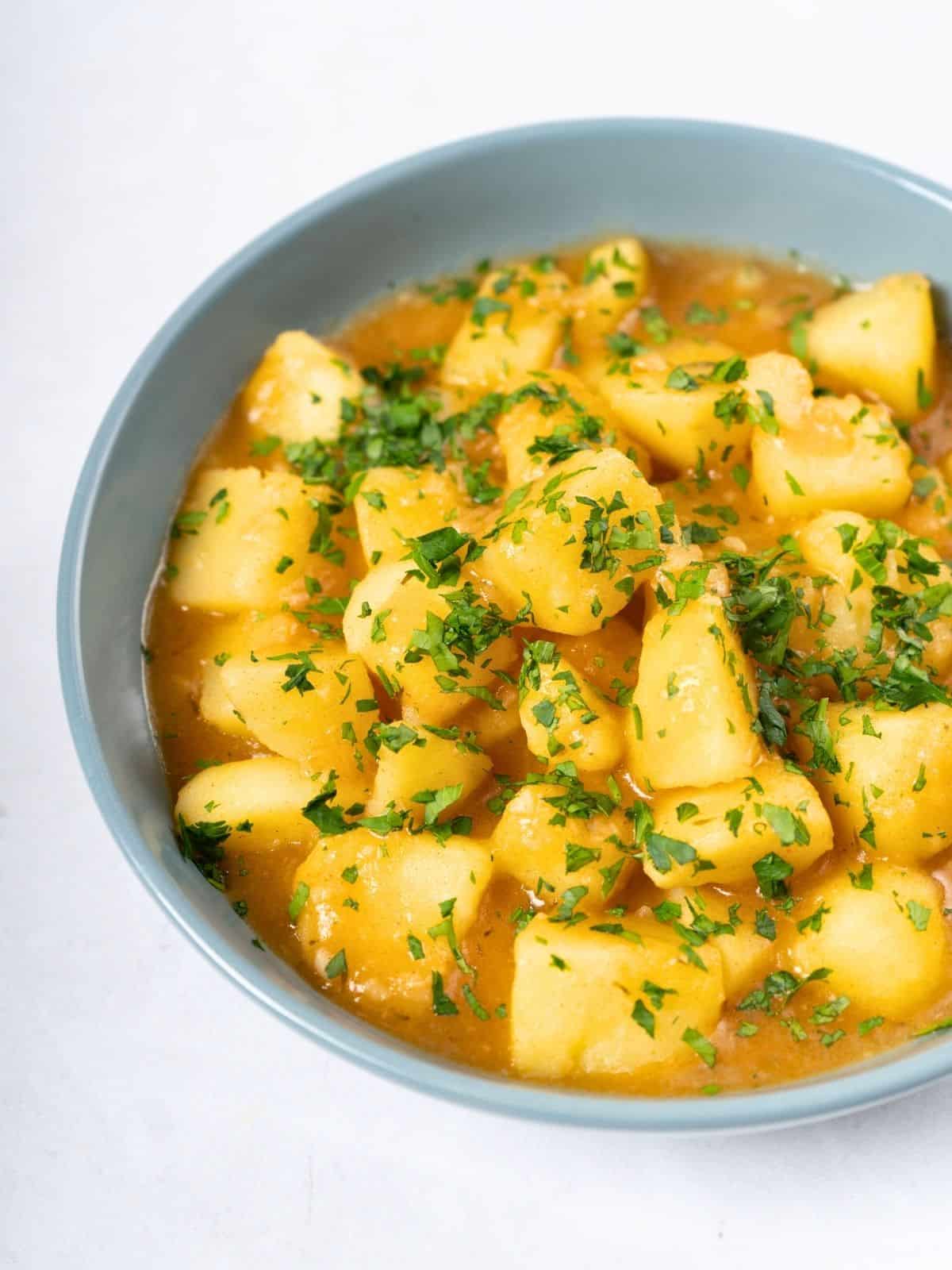 a bowl of stewed potatoes topped with fresh parsley.