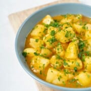 a bowl of stewed potatoes topped with fresh parsley.