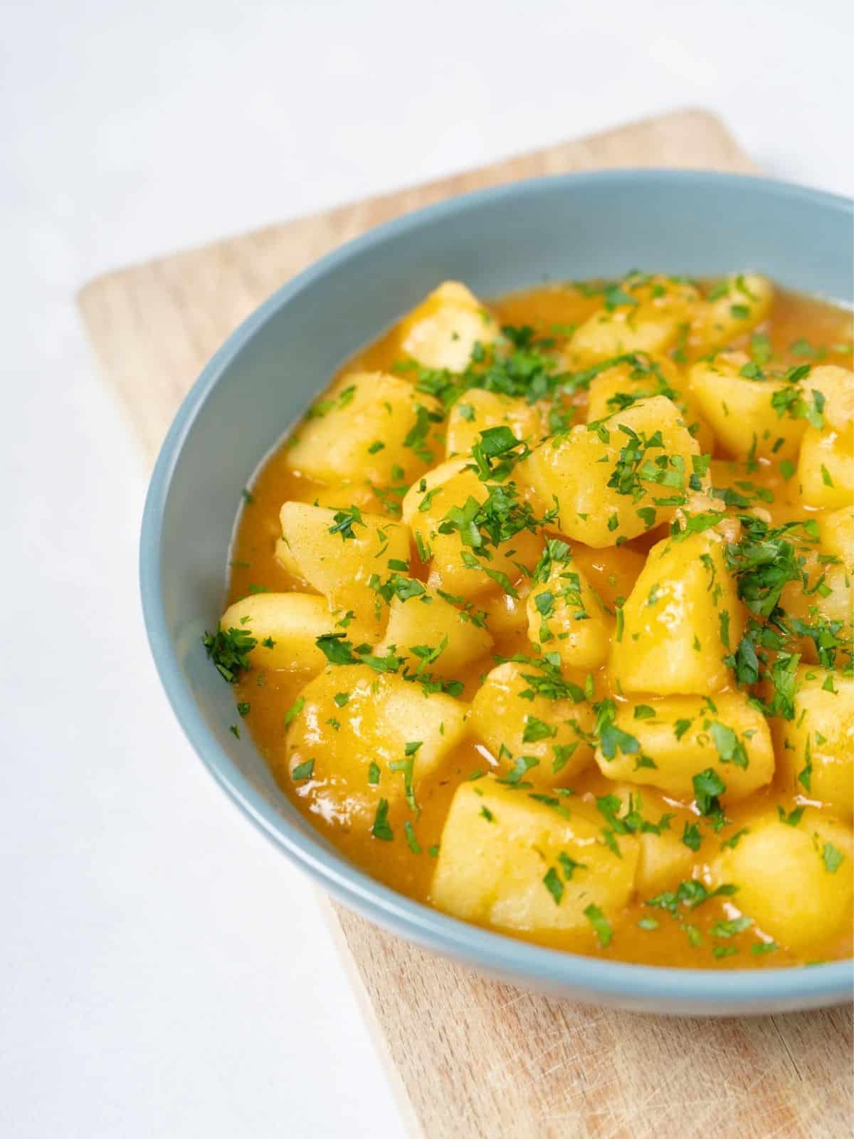 a bowl of stewed potatoes topped with fresh parsley.