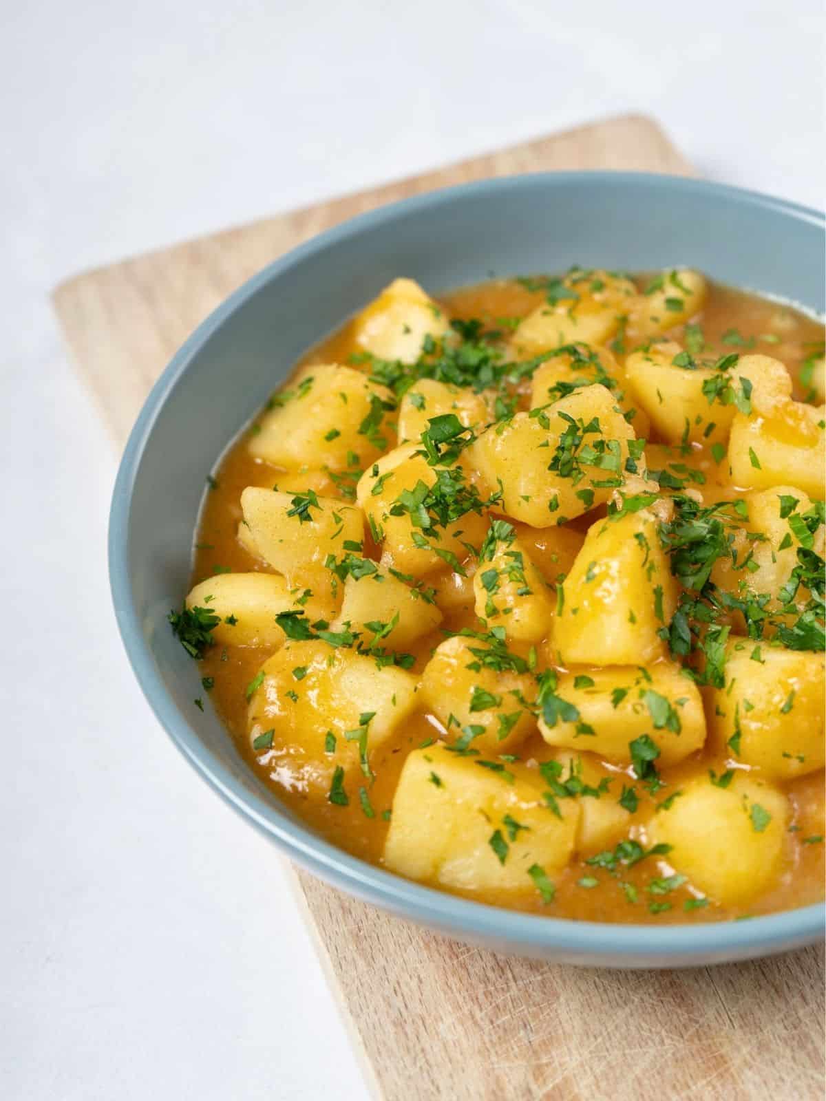 a bowl of stewed potatoes topped with fresh parsley.