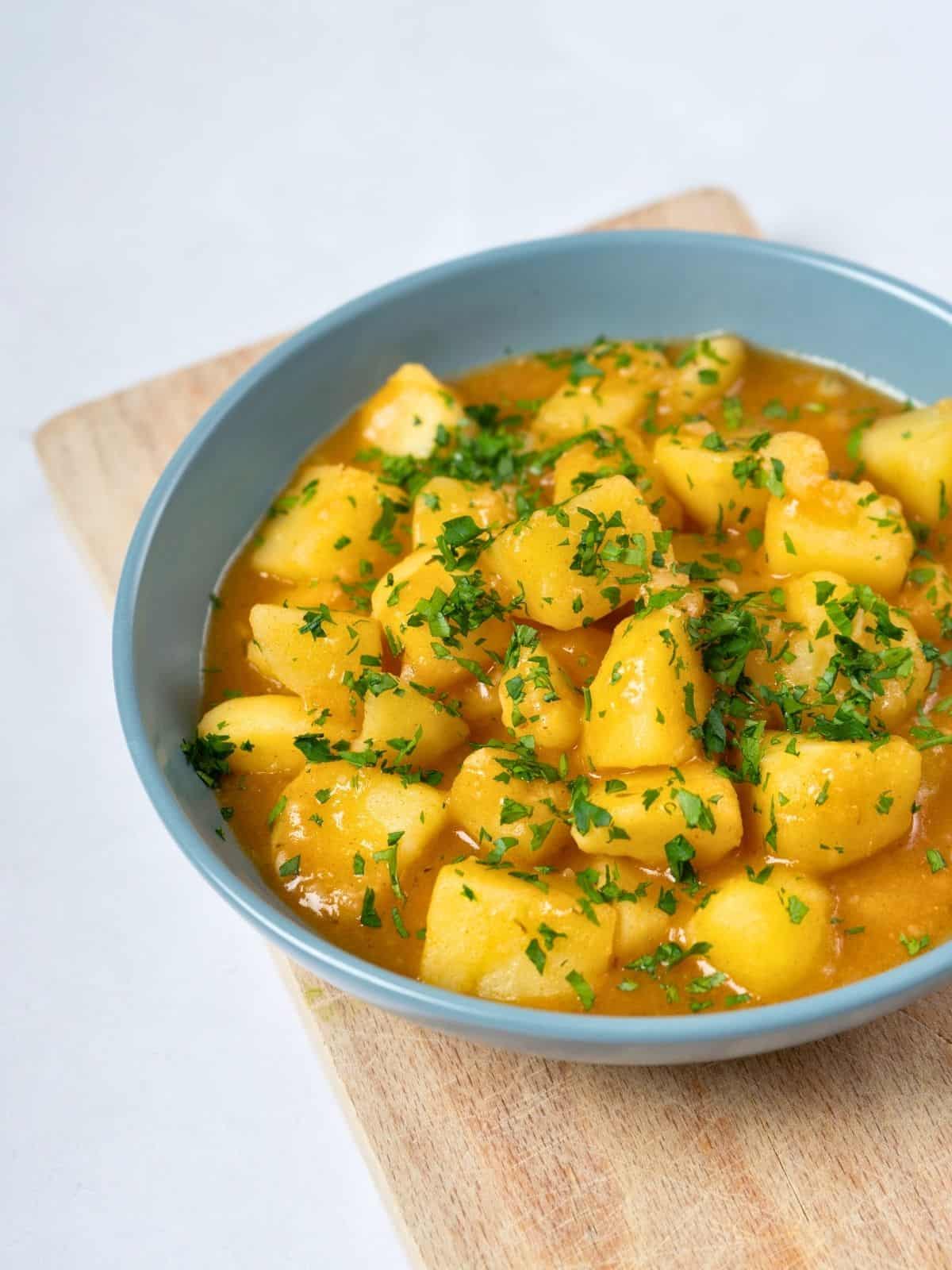 a bowl of stewed potatoes topped with fresh parsley.