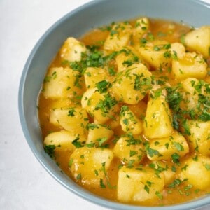 a bowl of stewed potatoes topped with fresh parsley.