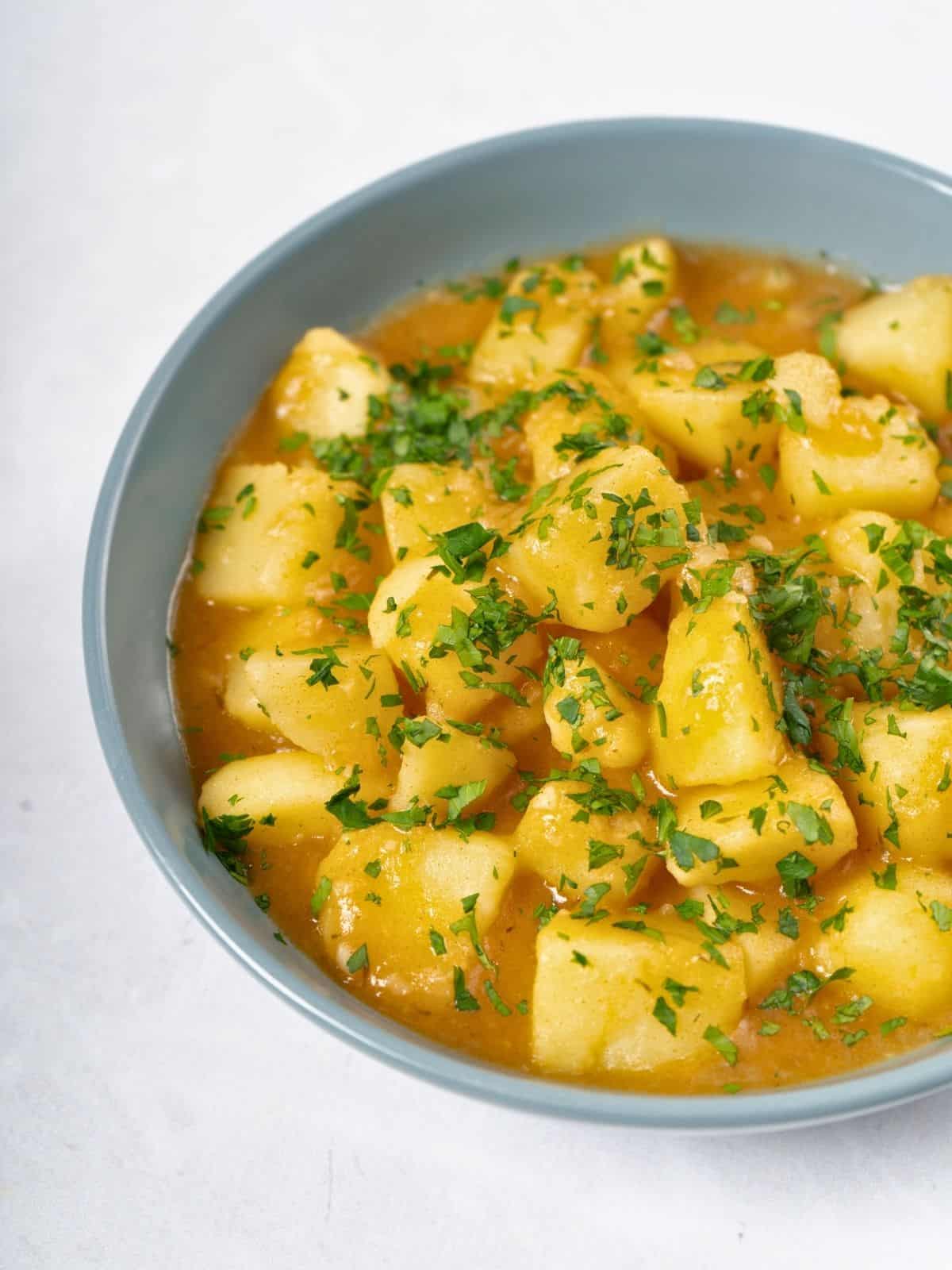 a bowl of stewed potatoes topped with fresh parsley.