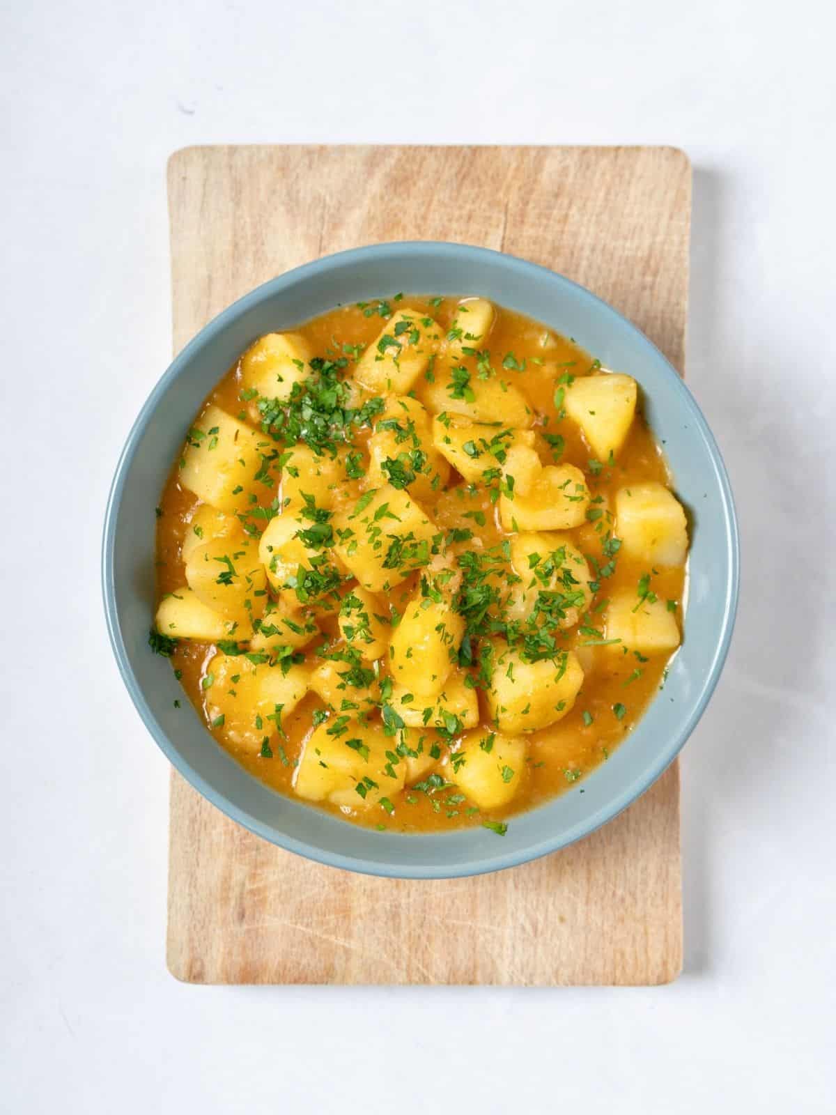 a bowl of stewed potatoes topped with fresh parsley.