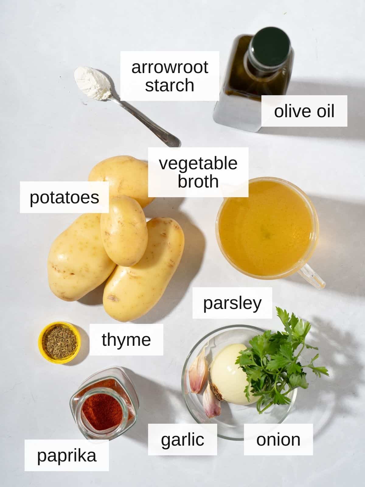 ingredients for stewed potatoes, including arrowroot starch, olive oil, vegetable broth, potatoes, parsley, thyme, paprika, garlic, and onion.