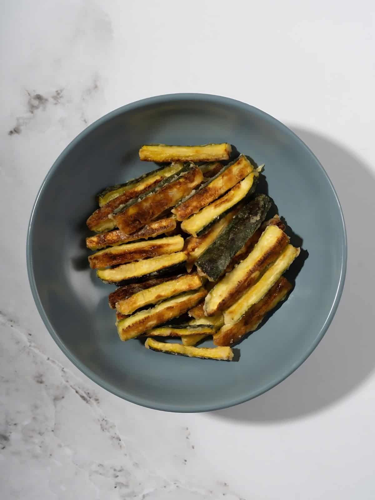 Crispy golden brown zucchini fries in a bowl.