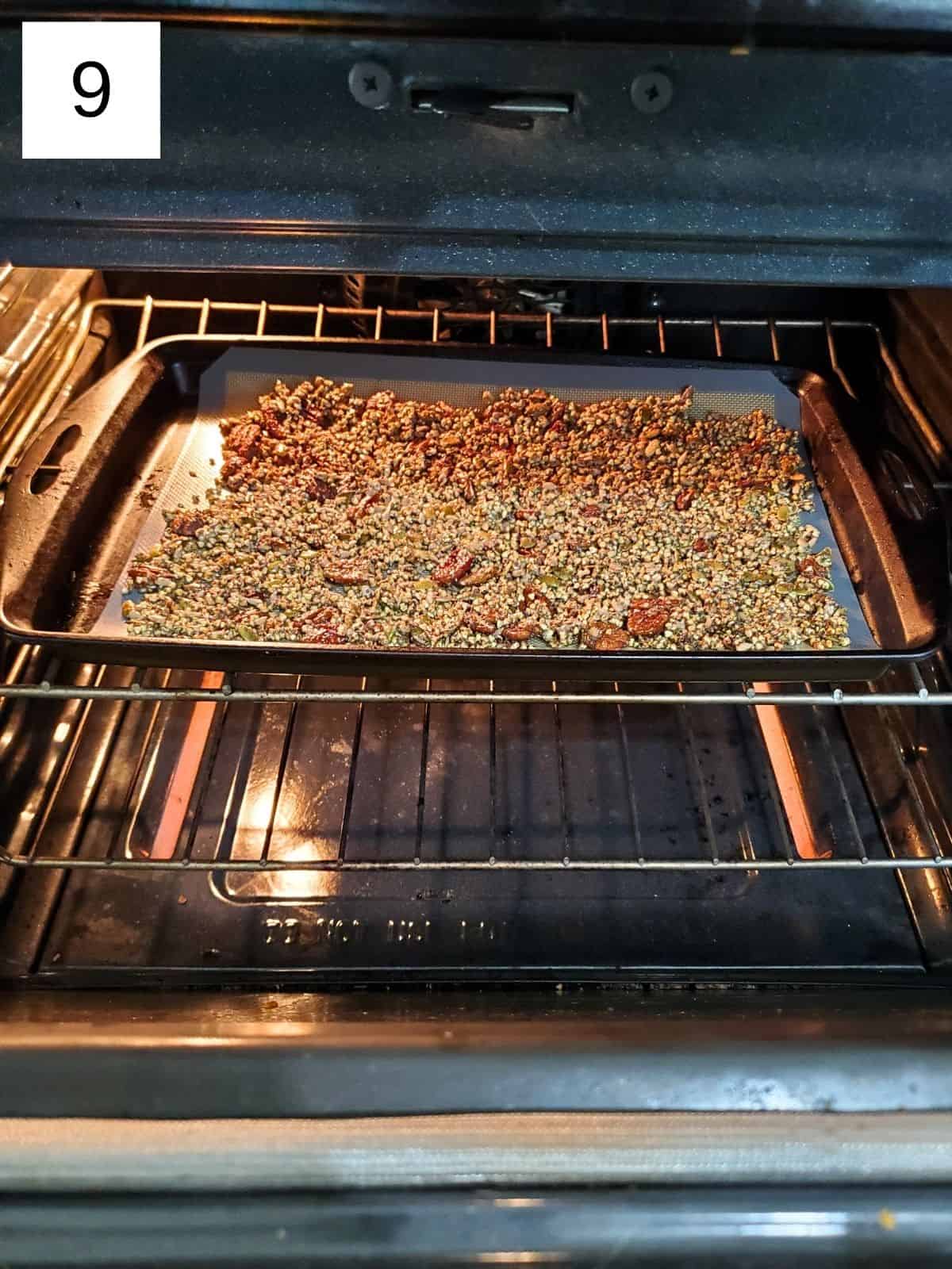 Granola nuts mixture on a tray being baked in an oven.