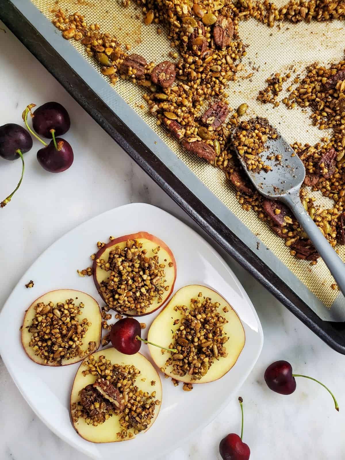 Slices of apples topped with granola nuts next to cherries.