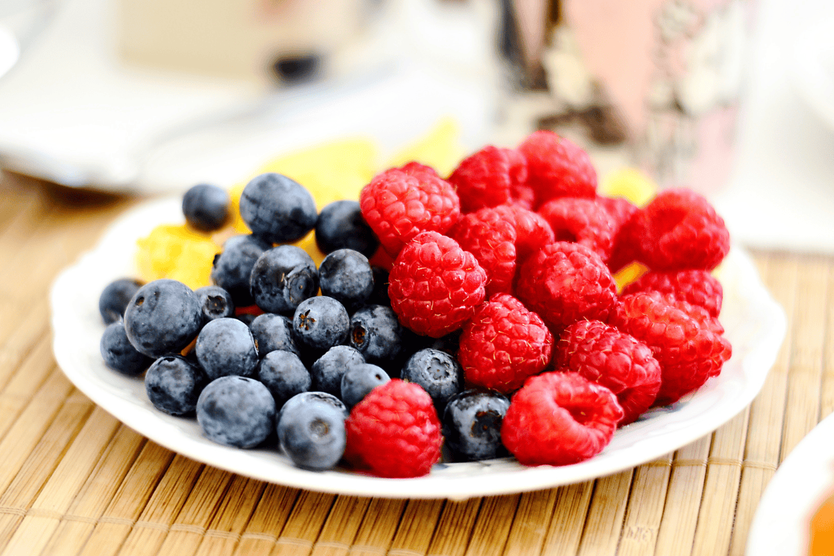 a plate full of fresh blueberries and raspberries.