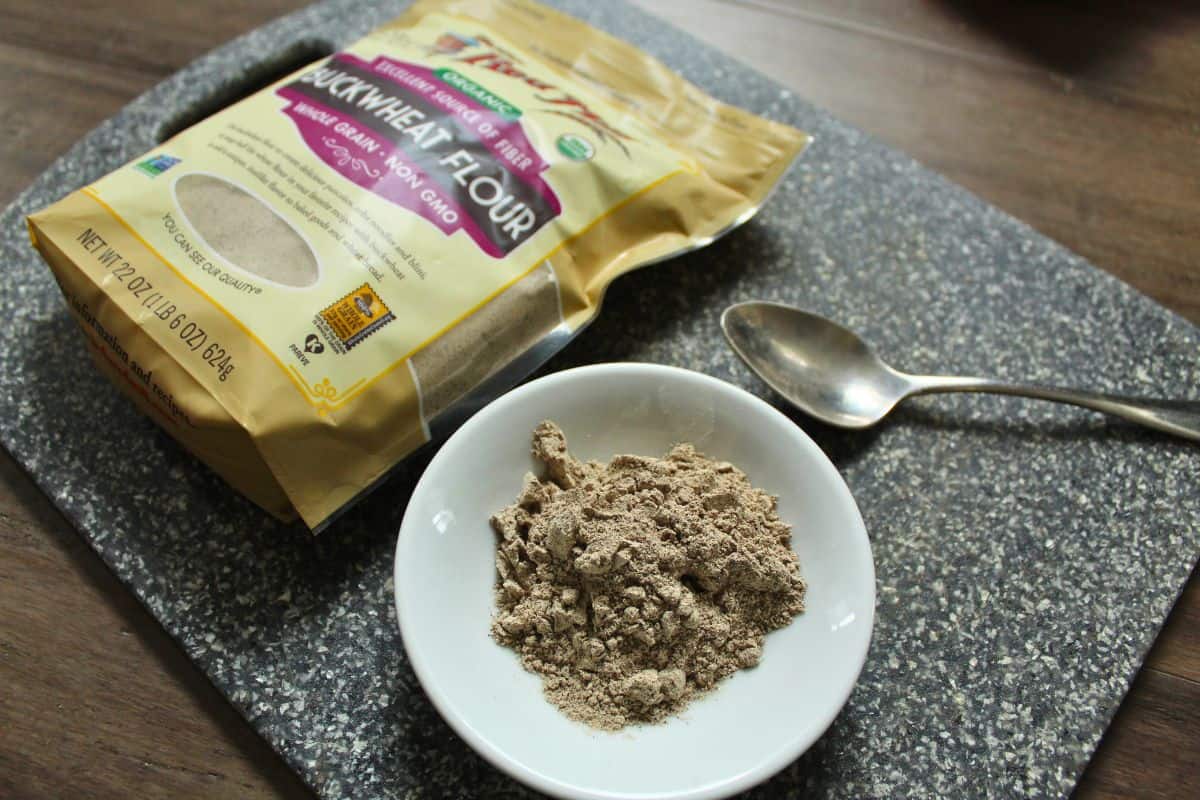 A pack of buckwheat flour next to a bowl of buckwheat flour. 