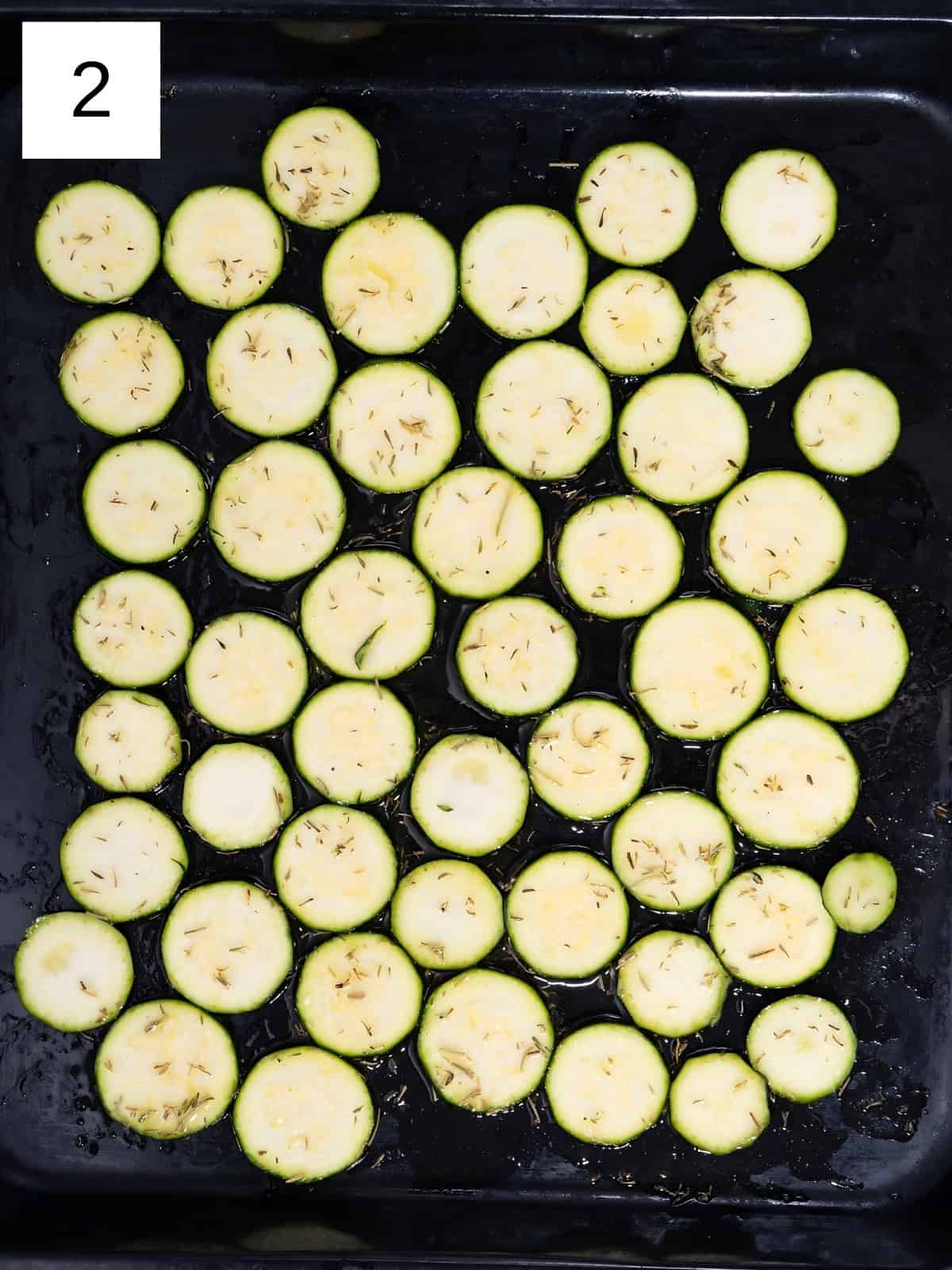 Coated zucchini disks laid on a baking tray.