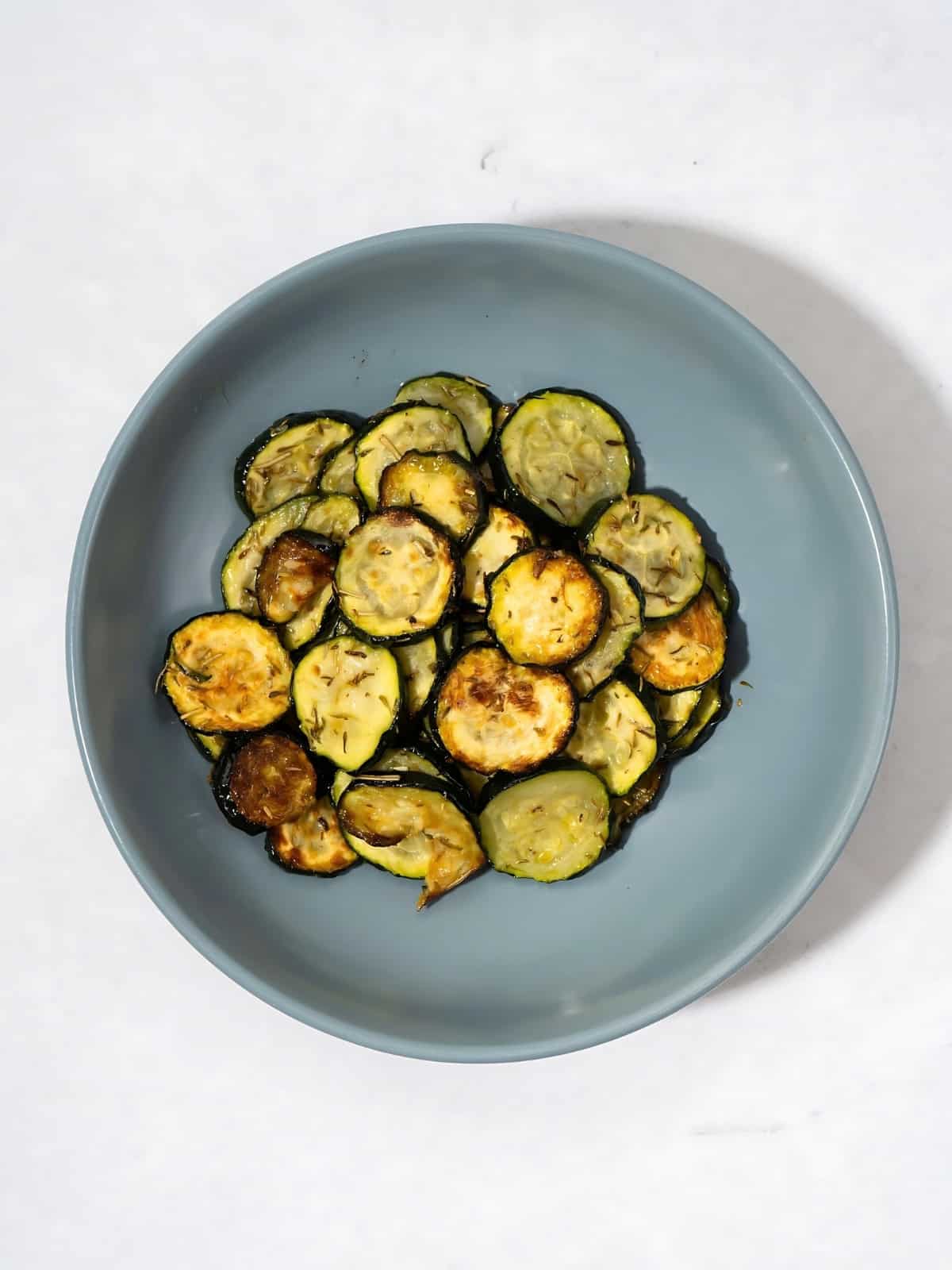 Herb roasted zucchini disks in a bowl.