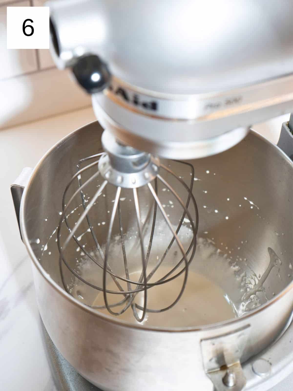 Whipping honey in a stand mixer to create a light, airy consistency.