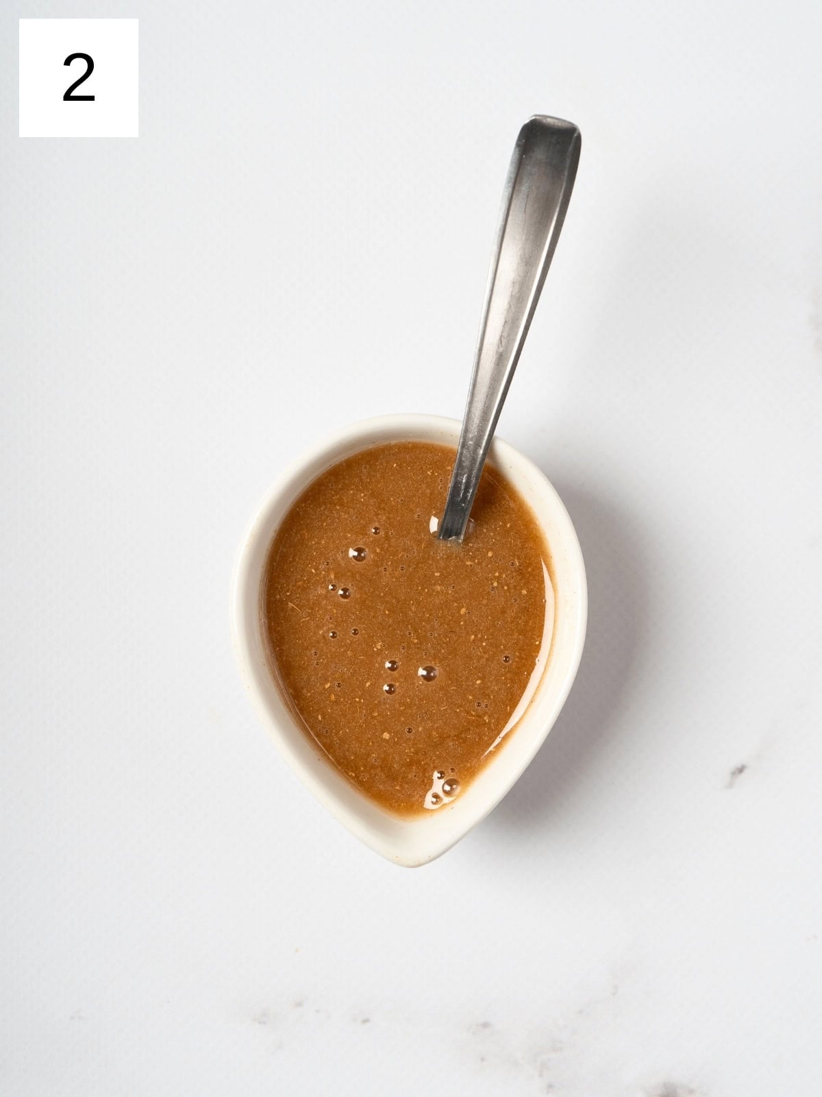 A bowl filled with a fragrant mixture of honey, cardamom, ginger powder, and lemon juice, showcasing a golden hue and a creamy texture, ready to be drizzled over pears.

