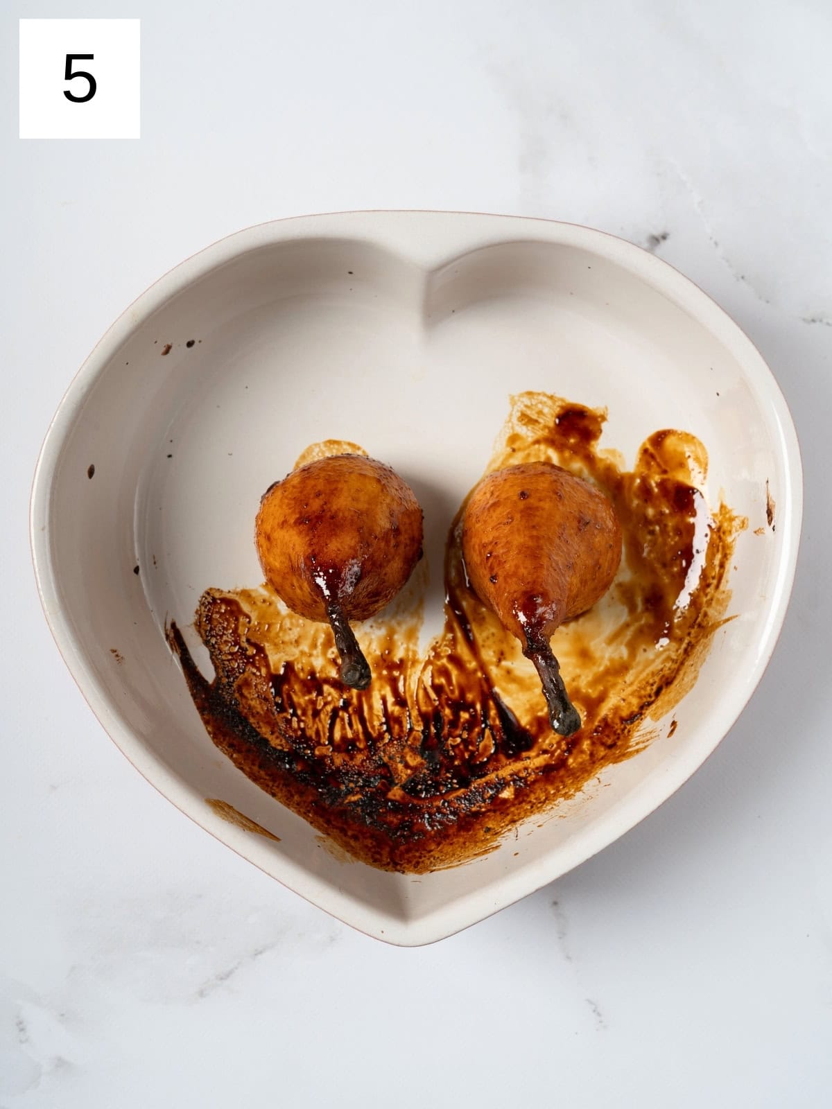 Two baked pears, perfectly golden and tender, resting on a plate, showcasing their caramelized exterior and inviting aroma, ready to be served as a delicious dessert.

