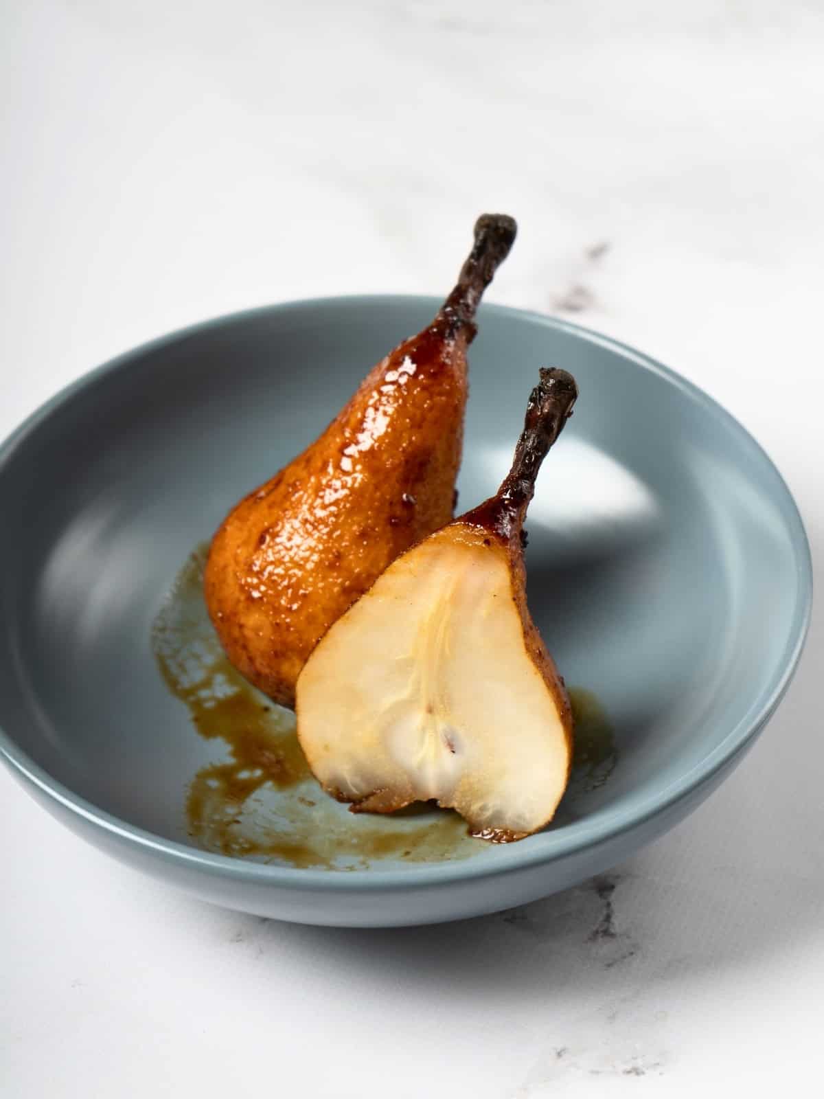 Whole baked pears, golden and tender, seasoned with a fragrant mixture of honey, cardamom, ginger, and lemon juice, beautifully arranged on a serving plate.