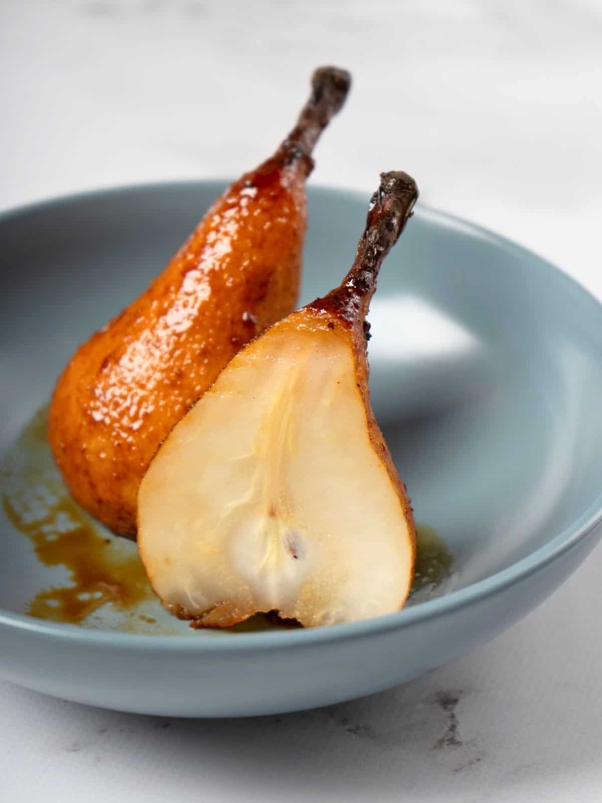 Whole baked pears, golden and tender, seasoned with a fragrant mixture of honey, cardamom, ginger, and lemon juice, beautifully arranged on a serving plate.