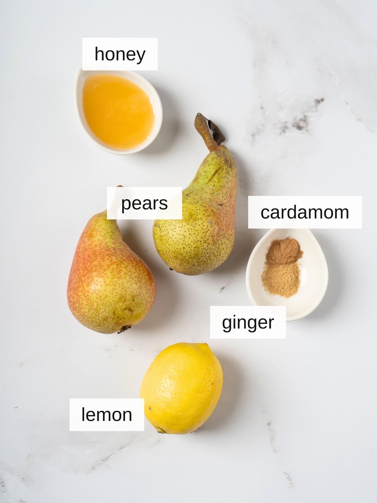 Ingredients for whole baked pears, including honey, ginger powder, cardamom, lemon juice, and pears.