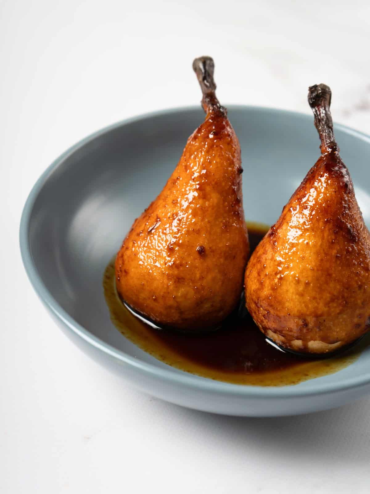 Whole baked pears, golden and tender, seasoned with a fragrant mixture of honey, cardamom, ginger, and lemon juice, beautifully arranged on a serving plate.