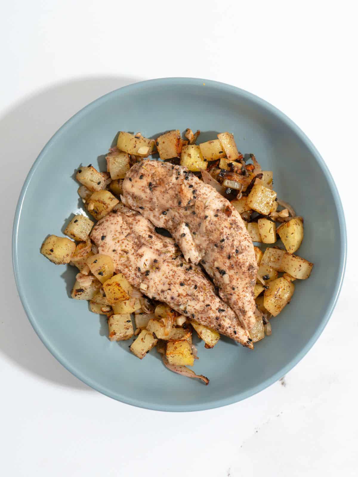 Plate of cooked sumac-seasoned chicken strips and sliced potatoes..