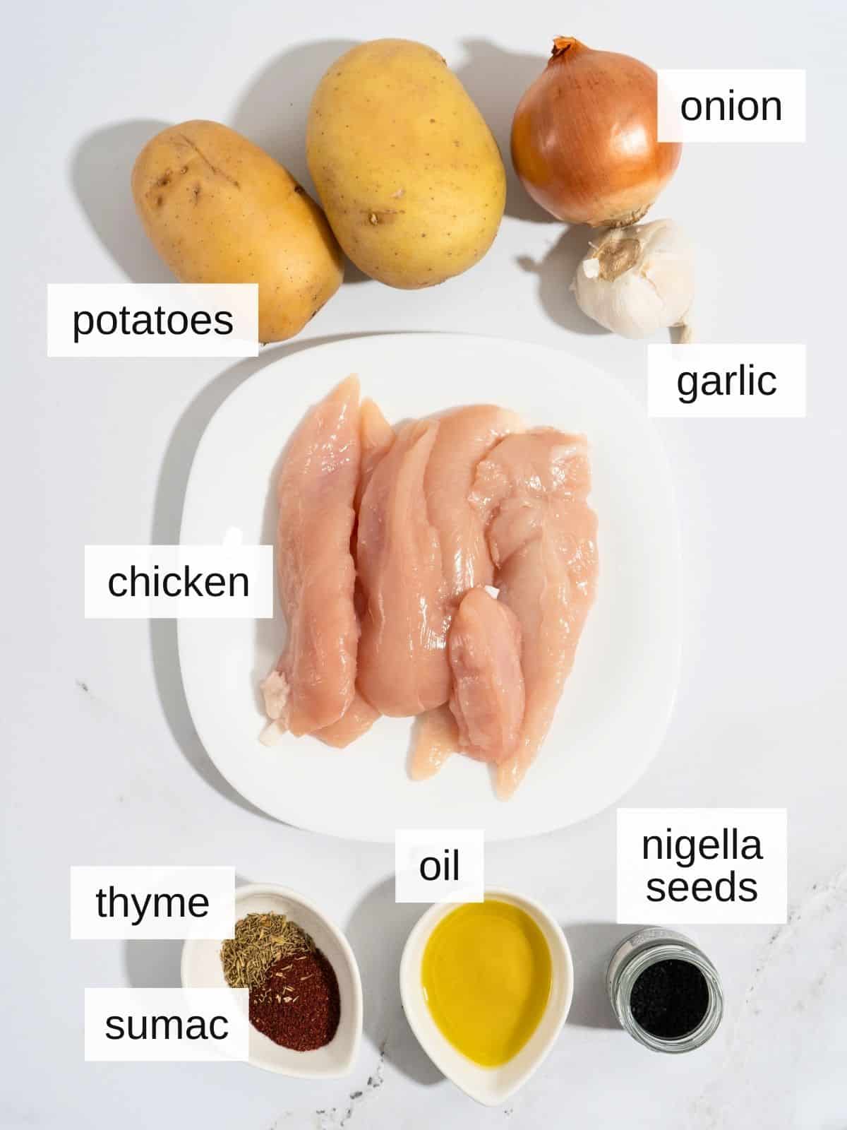 Ingredients for onion sumac chicken, including potatoes, onion, garlic, chicken. oil, nigella seeds, thyme, and sumac.