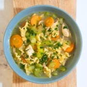 A steaming bowl of chicken noodle soup filled with tender chicken strips, colorful vegetables, and noodles.