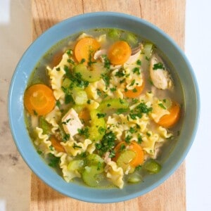 A steaming bowl of chicken noodle soup filled with tender chicken strips, colorful vegetables, and noodles.