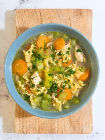 A steaming bowl of chicken noodle soup filled with tender chicken strips, colorful vegetables, and noodles.