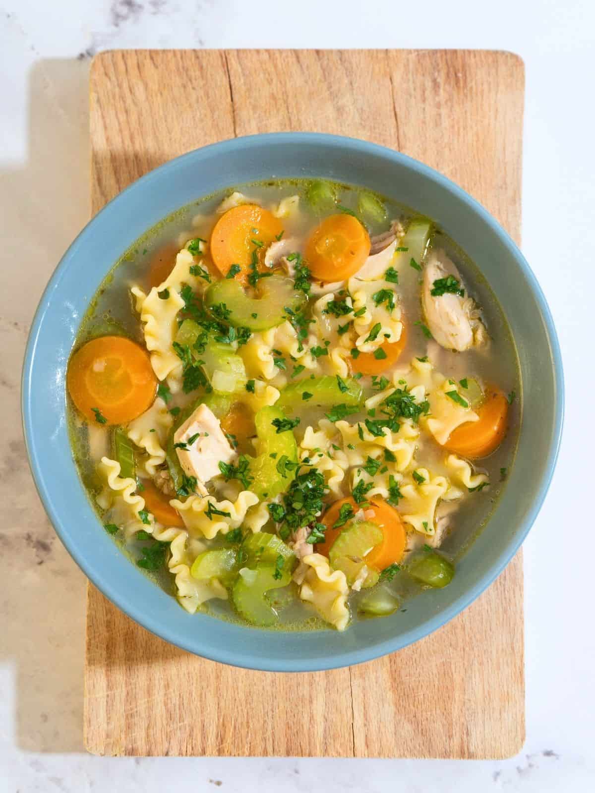 A steaming bowl of chicken noodle soup filled with tender chicken strips, colorful vegetables, and noodles.