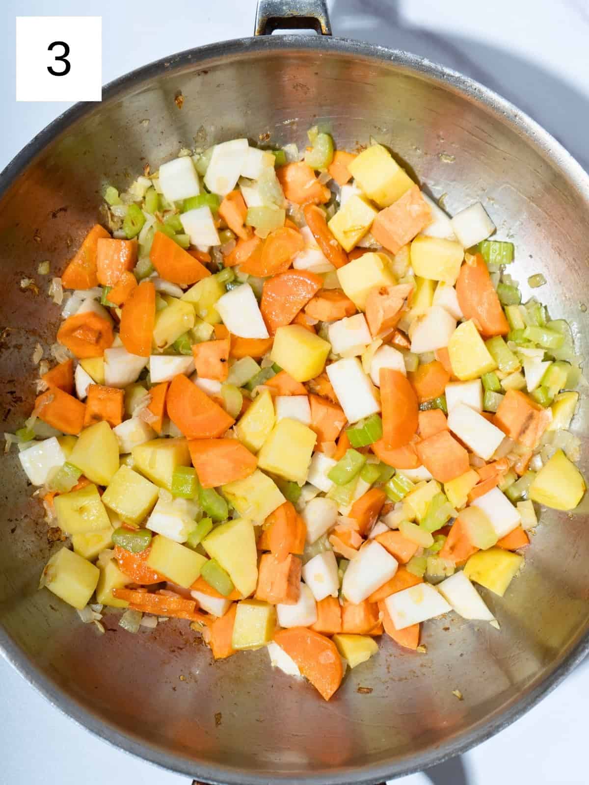 Chopped onion and garlic sautéing in a pot, followed by sliced carrots, diced potatoes, chopped celery, cubed rutabaga (or turnip), and sweet potato, all stirred together to create a flavorful base for vegetable stew.