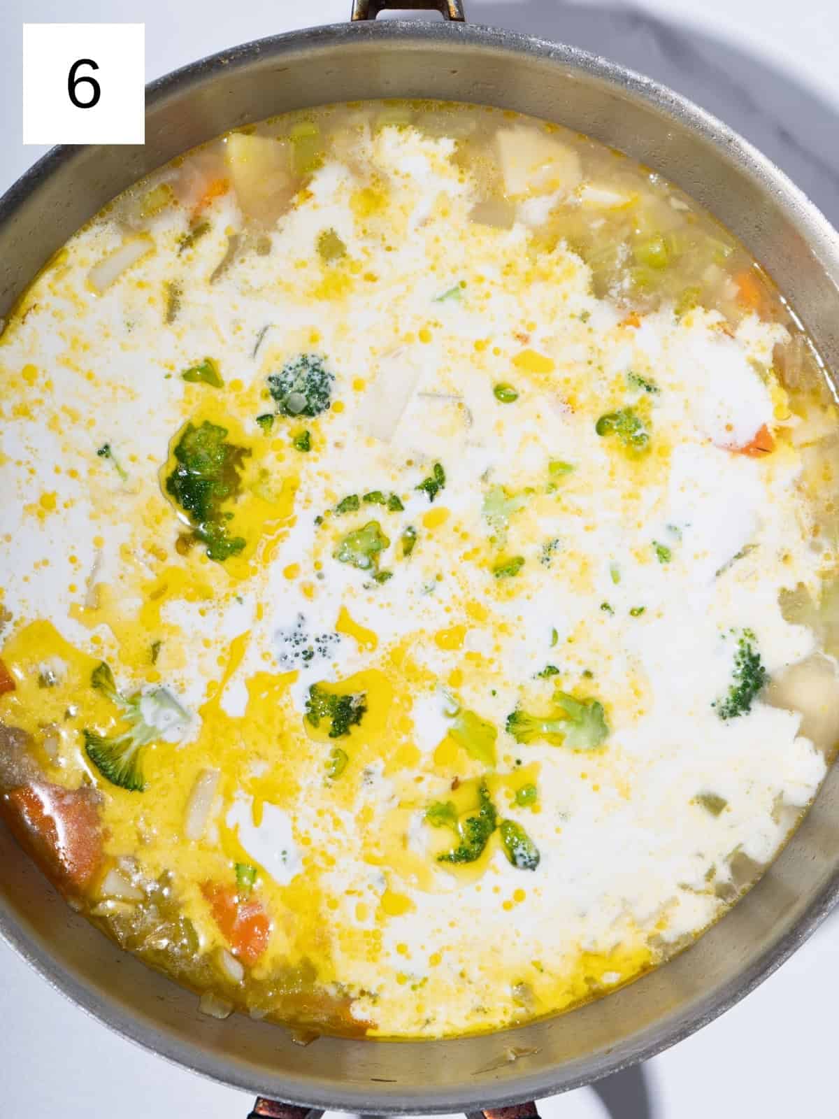 Chopped vegetables stirred together in a pot, with vegetable broth and coconut milk poured in.