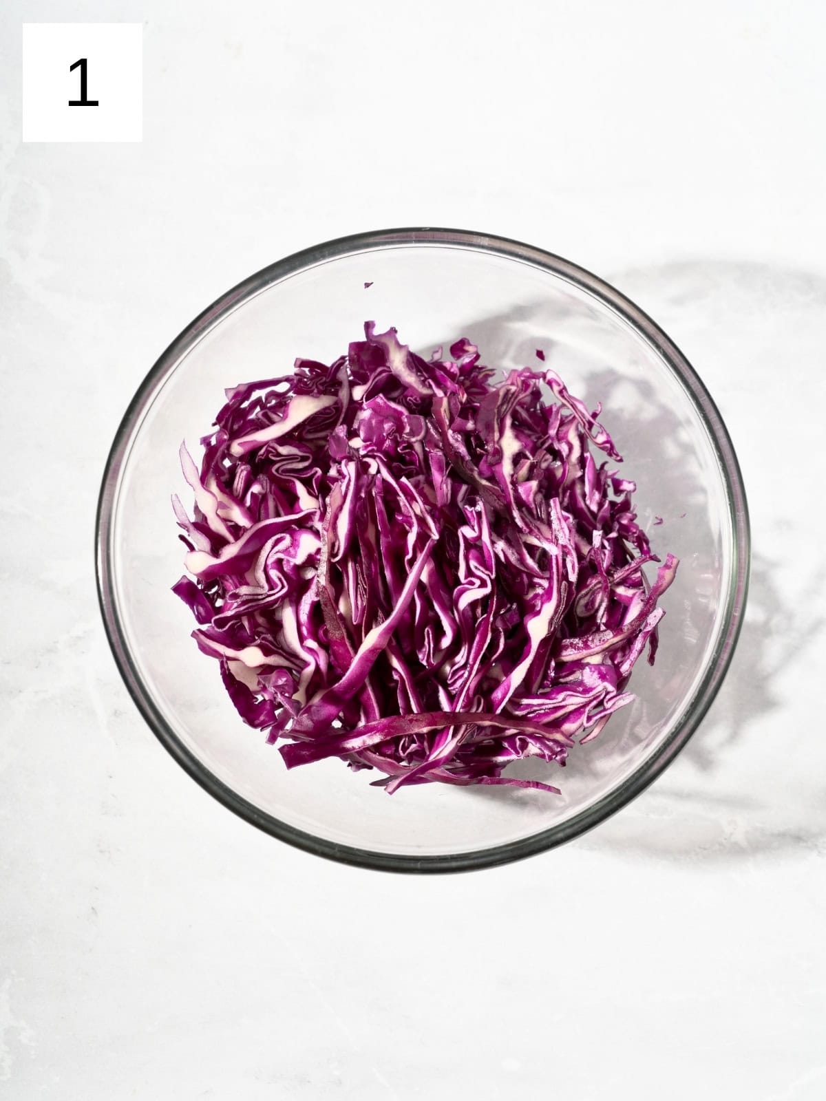 Thinly sliced purple cabbage in a bowl.