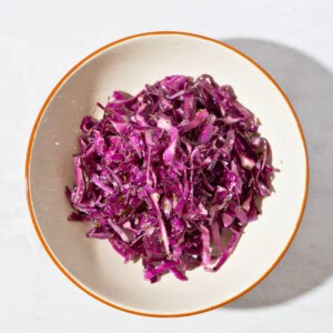 Colorful cabbage salad coated with Italian seasoning dressing, showcasing thinly sliced purple cabbage and a drizzle of olive oil, served in a bowl.