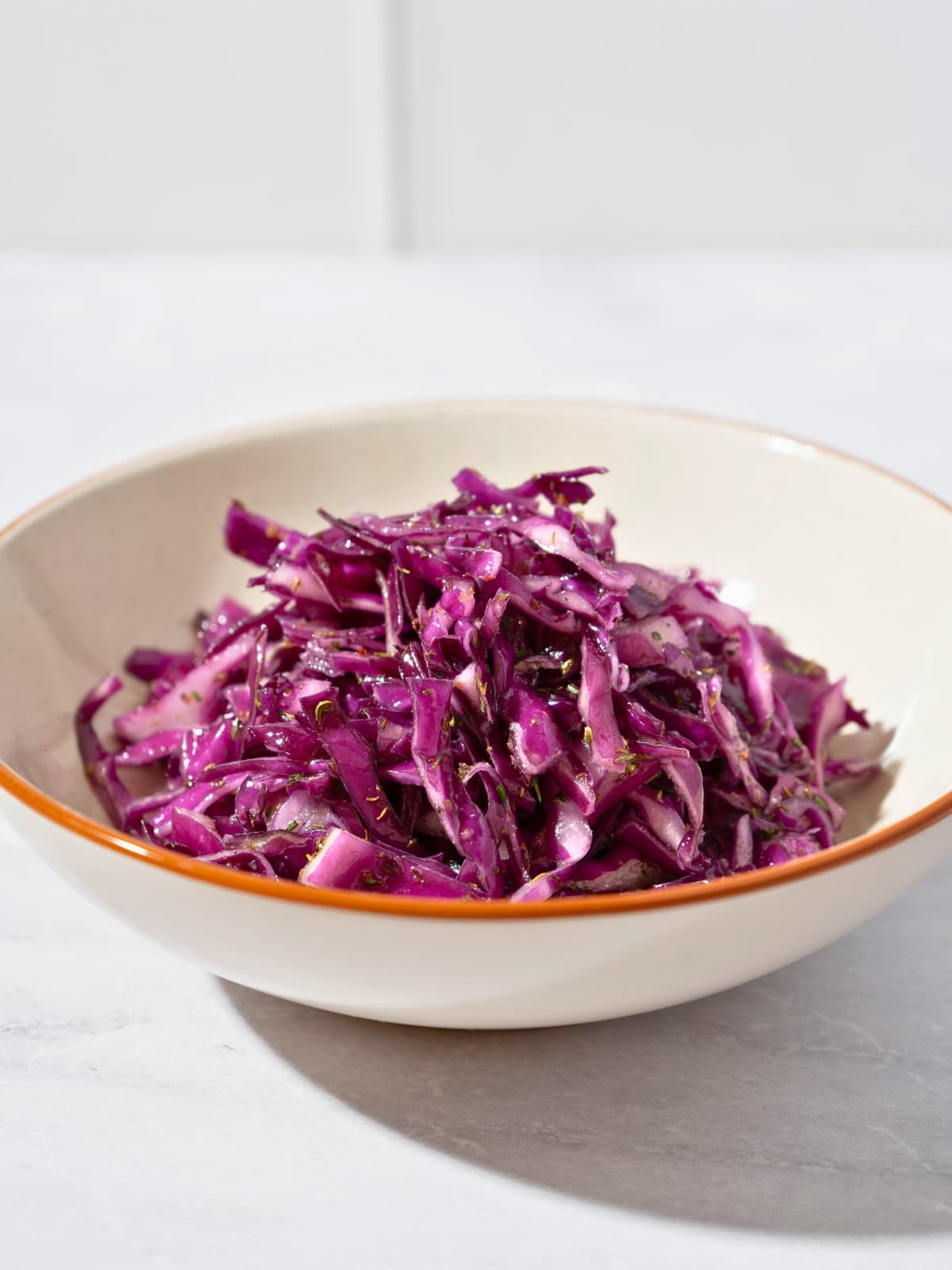 Colorful cabbage salad coated with Italian seasoning dressing, showcasing thinly sliced purple cabbage and a drizzle of olive oil, served in a bowl.