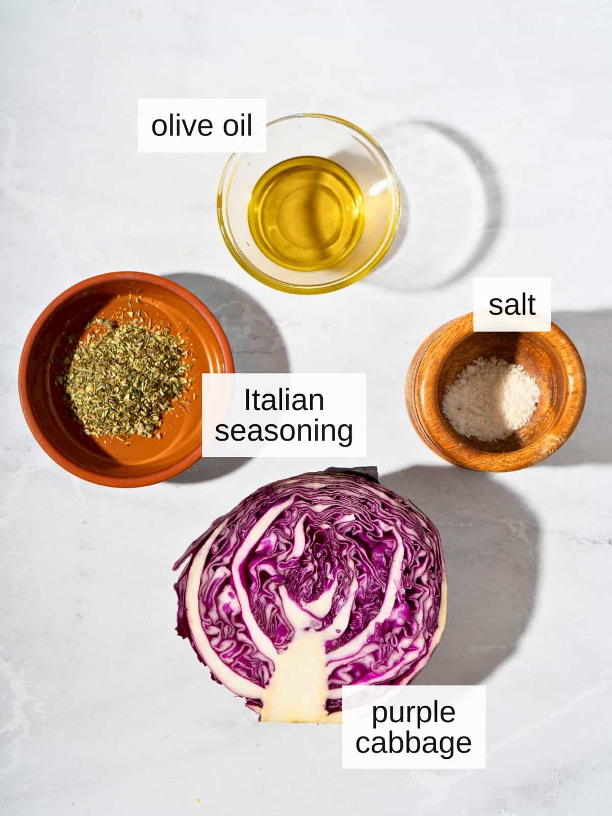 Ingredients for cabbage salad, including olive oil, salt, Italian seasoning blend, and purple cabbage.