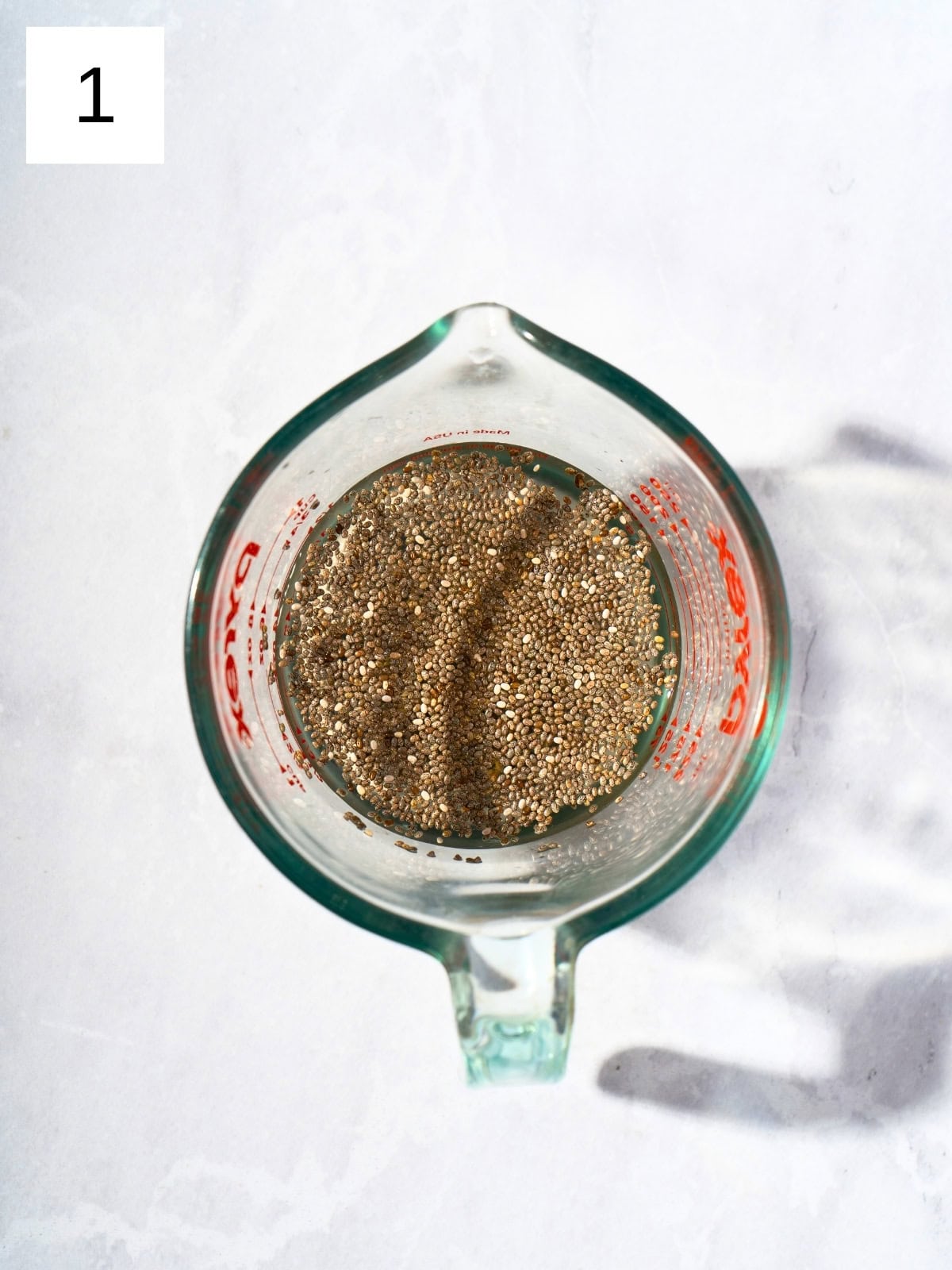 A mixture of chia seeds and apple juice in a mixing cup.