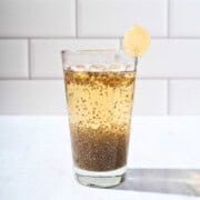Glass of refreshing chia apple juice garnished with fresh ginger slices, showcasing a healthy and vibrant beverage.