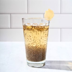 Glass of refreshing chia apple juice garnished with fresh ginger slices, showcasing a healthy and vibrant beverage.