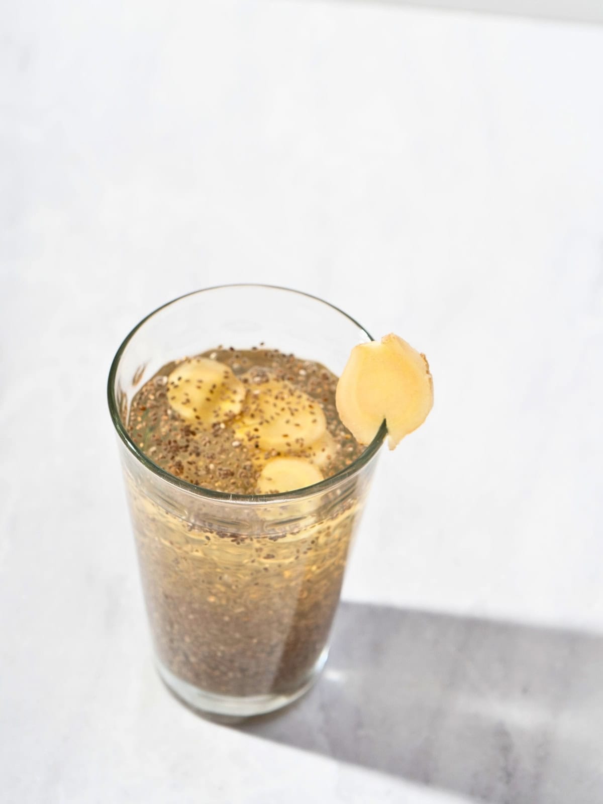 Healthy chia seed apple juice served in a glass with ginger slice garnish, perfect for a revitalizing beverage.