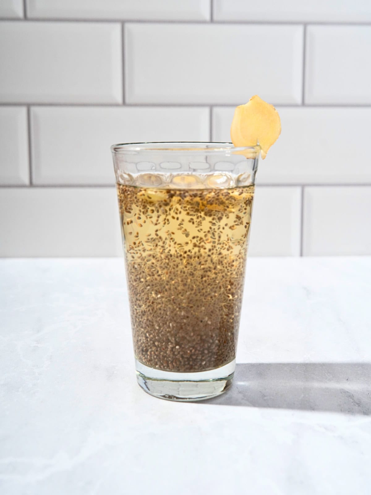 Refreshing glass of chia apple juice topped with thin ginger slices, highlighting a nutritious and hydrating drink.