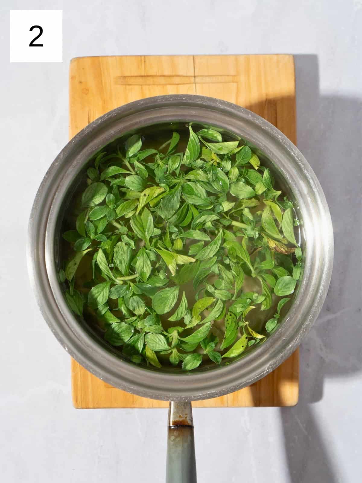 Fresh ginger slices and mint leaves in a saucepan filled with boiled water.