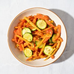 A colorful plate of stir-fried vegetables seasoned with oregano, featuring bell peppers, zucchini, and carrots sautéed to perfection.