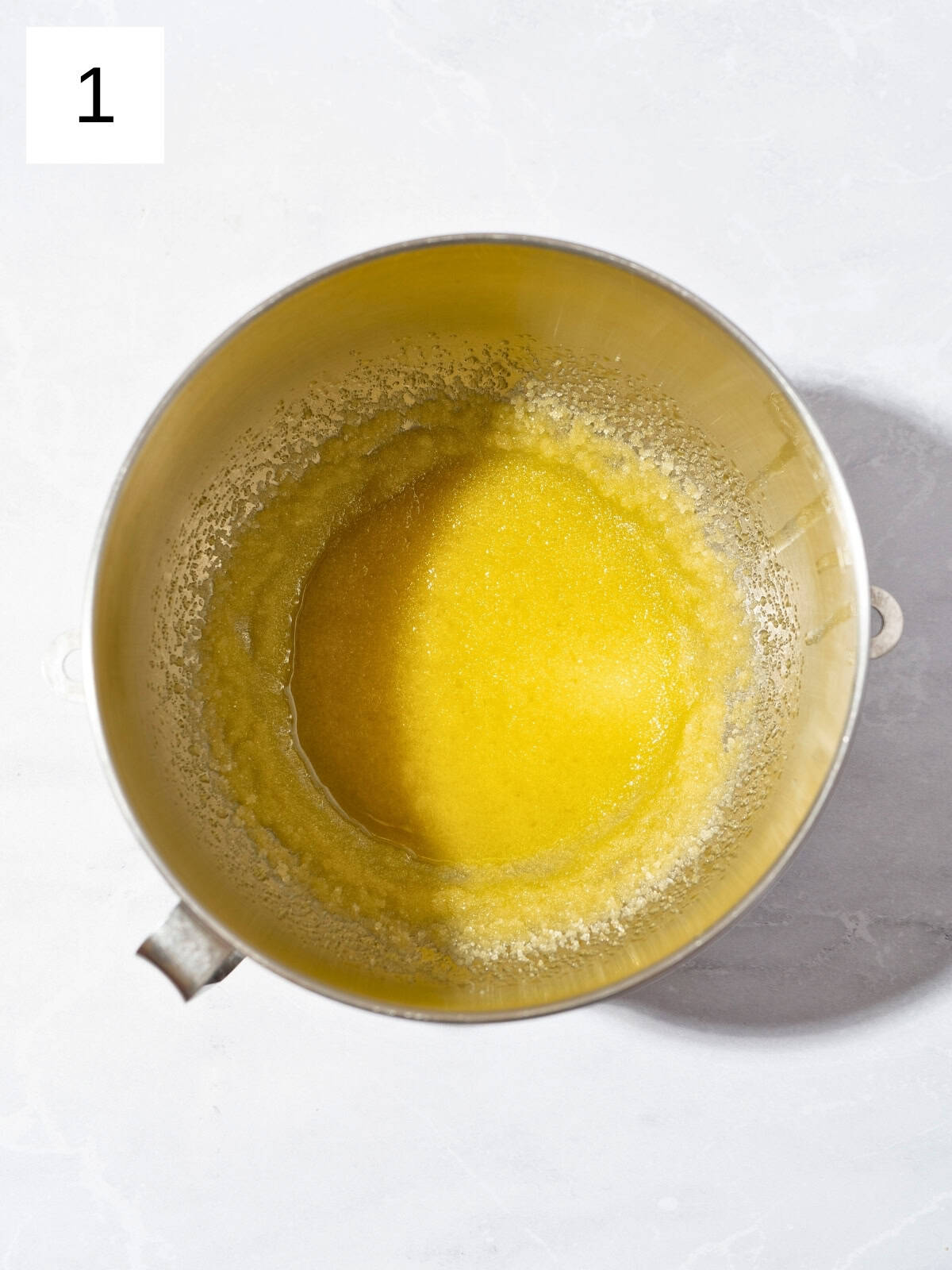 A mixture of olive oil and granulated sugar in a large mixing bowl.