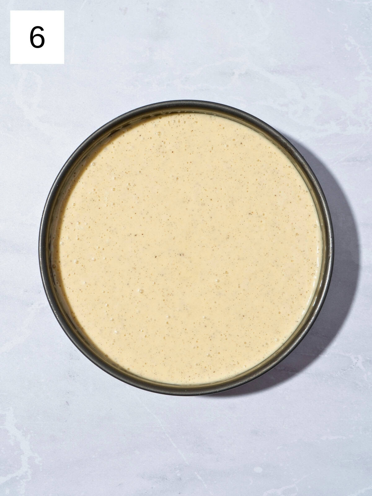 A mixture of vanilla olive oil cake batter in a cake pan, ready for baking.