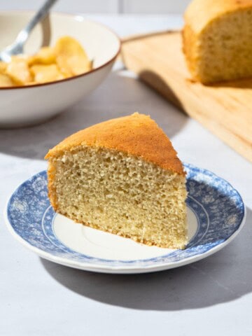 A slice of moist dairy-free vanilla cake served on a white plate, showcasing its tender crumb and light texture.